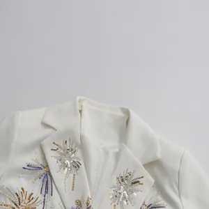 Close-up detail of elegant gold and silver firework sequin embroidery on white blazer