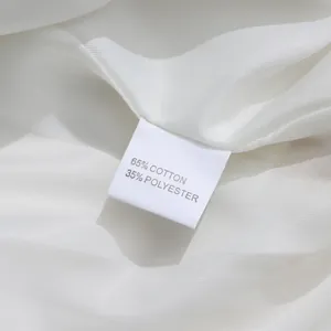 Detail of white sequined suit fabric showing 65% cotton and 35% polyester care label