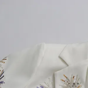 Close-up detail of colorful firework embroidery and sequins on white blazer lapel