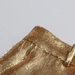 Macro detail showing the texture of gold sequins on a luxury blazer and trousers set.