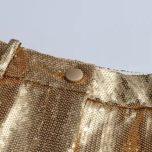 Detail shot of high-end golden sequin suit trousers showing texture and button