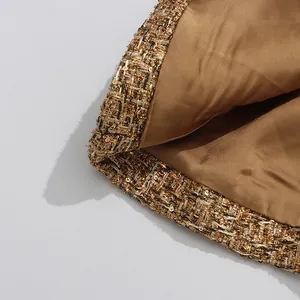 Close-up of high-quality gold tweed texture and smooth satin lining on a women's jacket