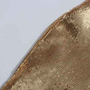 Close-up detail showing the dense texture of golden sequins on a luxury suit jacket.