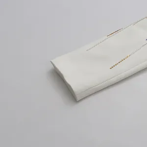 Close-up detail of golden embroidery and pearl fringe on a white blazer sleeve