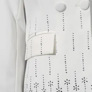 Close-up of white blazer featuring intricate vertical rhinestone lines and floral patterns