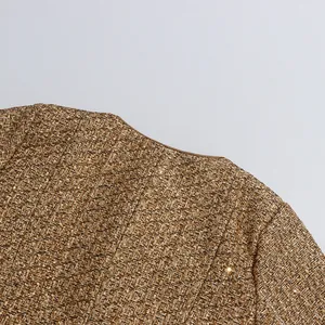 Close-up detail of a brown tweed jacket with shimmering gold sequins and round neck