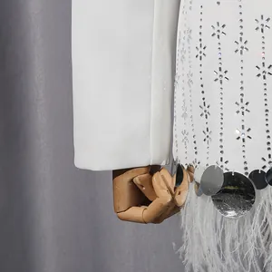 Close-up of white blazer featuring ostrich feather trim and silver sequin patterns.