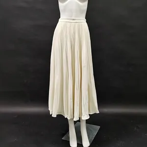 Détail montrant la texture d'une jupe midi plissée à taille haute de couleur crème.