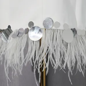 Close-up detail of ostrich feather trim and silver sequins on white blazer hemline
