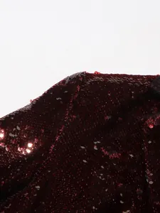 Close-up macro view of high-quality burgundy sequins on a luxury evening blazer.