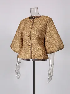 Elegant gold tweed jacket with puff sleeves and decorative gold buttons on clear mannequin