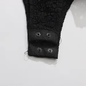 Close-up of snap button closure on black lace bodysuit with textured fabric detail.