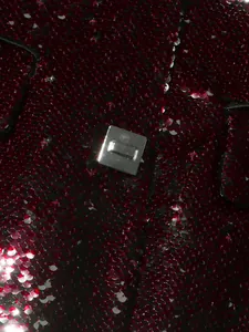 Close-up detail of red sequined blazer featuring a modern square metallic clasp design