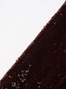 Close-up macro detail of burgundy sequin fabric on a high-end women's blazer jacket