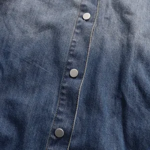 Close-up detail of vintage denim shirt showing fabric texture and silver metal buttons.