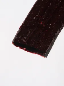 Close-up of elegant burgundy sequins on the sleeve of a high-quality women's blazer.