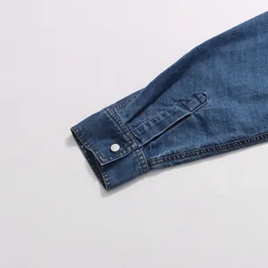 Close-up detail of vintage denim shirt cuff with silver button and stitching