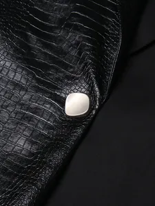 Close-up van de krokodillenleer textuur en zilveren knoop op deze zwarte mouwloze vest