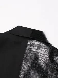 Detailopname van zwart mouwloos vest met patchwork van imitatie krokodillenleer.