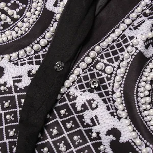 Macro view of Palace style printed suit jacket with pearl bead embellishments and snap button.