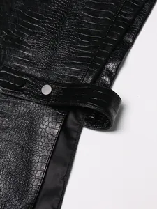 Detailopname van een zwart kunstleren vest met krokodillenreliëf en metalen knopen
