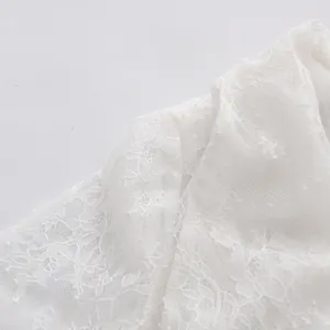 Nahaufnahme von zarter Blumenstickerei aus Spitze auf einer weißen transparenten Bluse