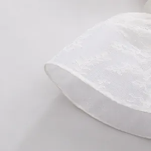 Detailaufnahme der weißen Blumen-Spitzenstruktur und Volantsaum einer eleganten französischen Bluse