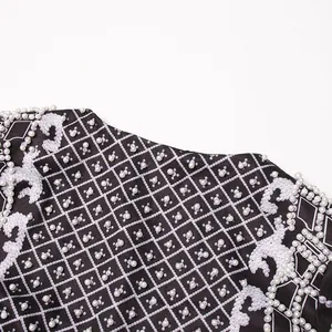 Close-up of heavy industry pearl beads and ornate print on a royal style suit jacket