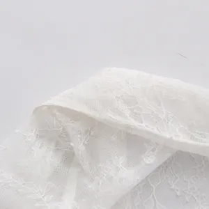 Detailansicht der zarten weißen Blumenstickerei am Kragen dieser eleganten Spitzenbluse.