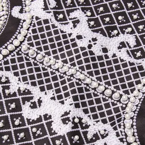 Close-up of elegant court style print and white pearl bead embellishments on black blazer