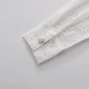 Detailaufnahme der eleganten weißen Spitzenmanschette mit floraler Stickerei und Knopf