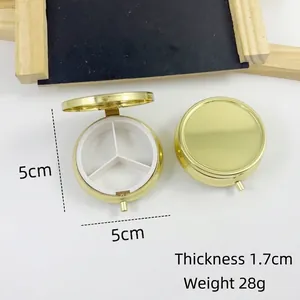 Detail van ronde gouden metalen pillendoos met 3 compartimenten en 5 cm afmetingen