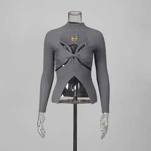Détail du pull en maille côtelée grise avec découpe torsadée et décoration oeil doré