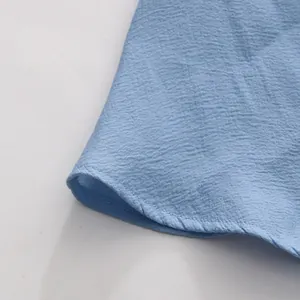 Close-up detail of light blue textured fabric and delicate ruffled hem stitching
