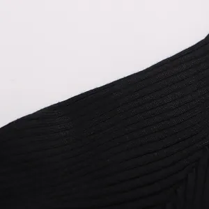 Gros plan sur la texture du tricot à côtes noires et les finitions de couture de haute qualité.