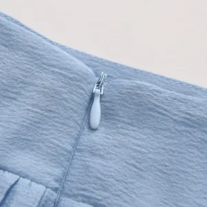 Detailed close-up showing the invisible zipper and refined fabric texture of light blue skirt