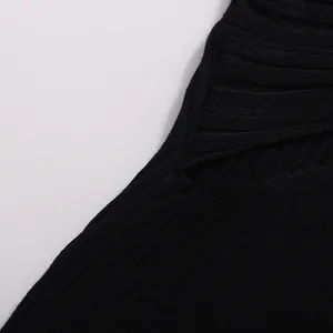 Détail montrant la texture en maille côtelée et la découpe torsadée d'un haut noir pour femme
