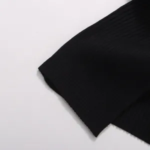 Gros plan sur la texture en maille côtelée fine et le tissu noir de ce haut pour femmes