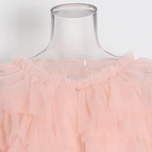 Detalle de volantes de tul rosa en capas y el escote elástico con volantes de blusa.