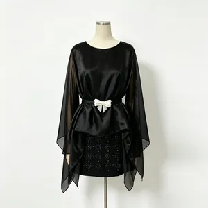 Dettaglio della camicetta in chiffon nero con maniche trasparenti e cintura a fiocco