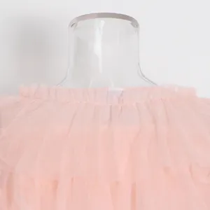 Primer plano detallado del elegante escote con volantes de malla rosa en una blusa de verano.