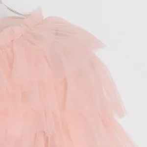 Primer plano detallado de volantes de tul de malla rosa en una blusa de verano de mujer.