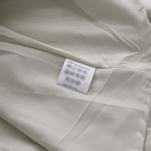 Gedetailleerde weergave van het 100% polyester waslabel op een luxe witte satijnen jurk