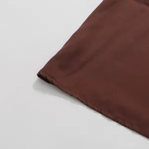 Detail of brown skirt hem showing neat stitching and high-quality fabric texture.