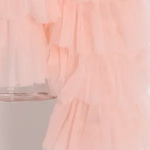 Primer plano de volantes de malla rosa escalonados en un elegante top ligero de verano
