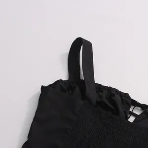 Detail shot of black sleeveless top featuring smocked bodice and wide shoulder straps.