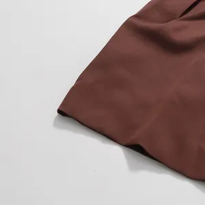 Detailed close-up showing the smooth brown fabric and clean hem of an elegant skirt.