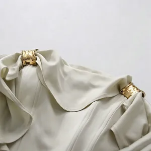 Detailopname van de elegante gedrapeerde halslijn en de gouden metalen gespen