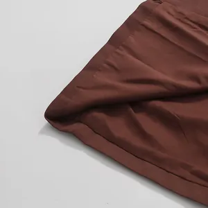Close-up detail of the smooth brown fabric and neat hemline of the elegant skirt.