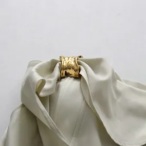 Detail van een elegante witte satijnen jurk met een luxe gouden metalen gesp voor de avond